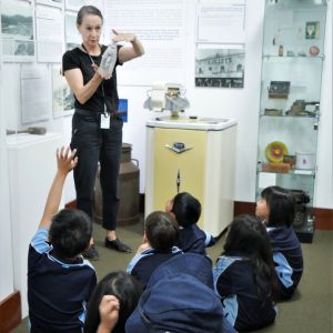 students on a excursion looking at a glass bottle with museum staff