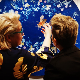 Two woman looking at a cyanotype and blue artwork surrounding it