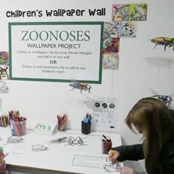 A person colouring in at the ZOONOSES Wallpaper colouring station