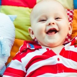 Baby smiling while on a colourful blanket