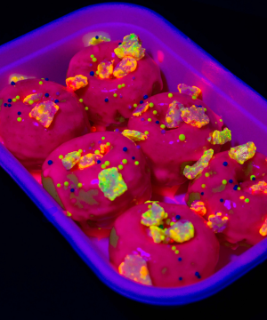 Six mini donuts with glowing popping candy pieces on them