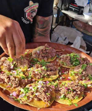 Person holding a platter with many tacos on them