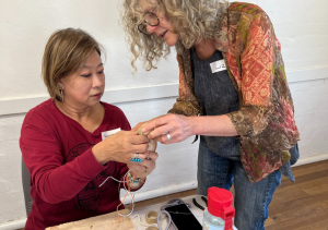 Liz walker showing another woman a bracelet at a workshop