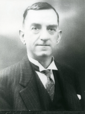 Portrait of Les Blackshaw wearing a black striped suit with a tie