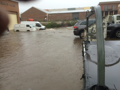 Flooding against a building and up to the top of the tyres of two parked white vans