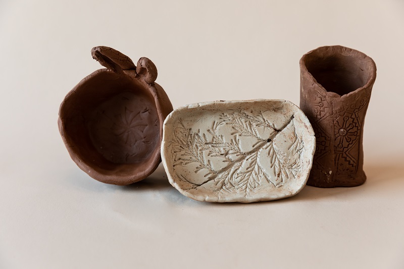 Three clay artwork pieces shaped like an oval tray, a bowl with rabbit ears, and a cylinder vase.