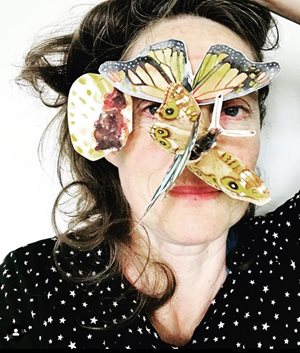 portrait photograph of the artist with paper butterflies all over her face