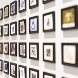 Many black framed prints against a white wall