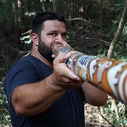 Image of Brenden Moore using an Aboriginal didgeridoo instrument