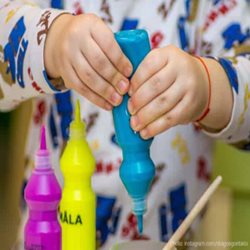 A child's hands squeezing a tube of paint.