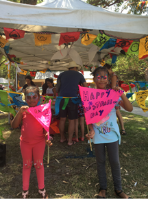 two little girls holding banners for Australia Day with a message saying happy Australian Dayon the park