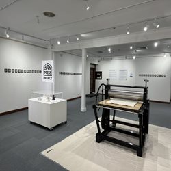 View of Open Print Exchange exhibition in Main Gallery, printing press in foreground.