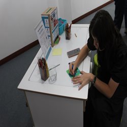 A woman drawing while sitting at a desk.