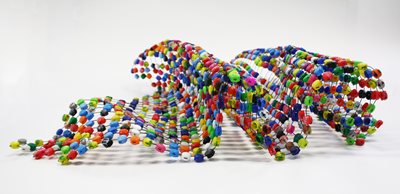 colorful artwork made out of small round pieces attached by string creating an estructure similar to a wave