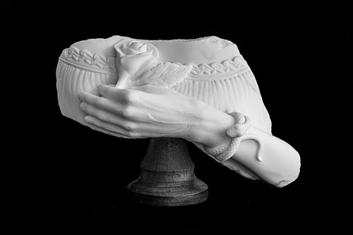 White and black picture of a white marble sculpture of a hand holding a rose