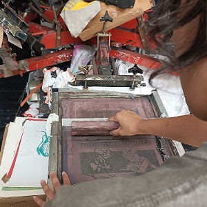 An artist using a screen printing press.